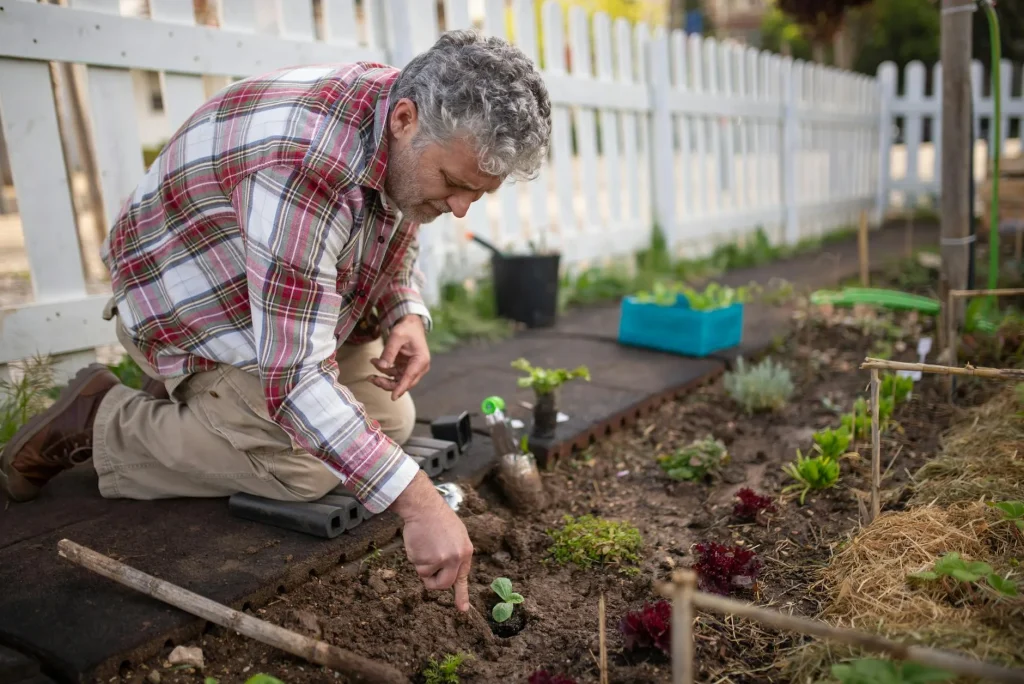 Gardener kneeling while weeding a flower bed