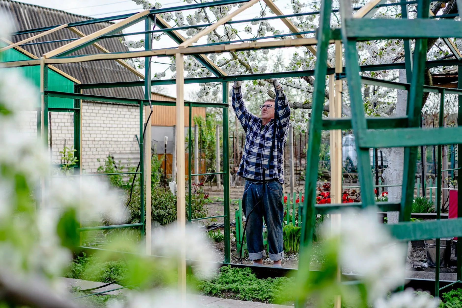 Person assembling a wooden raised bed kit in a garden