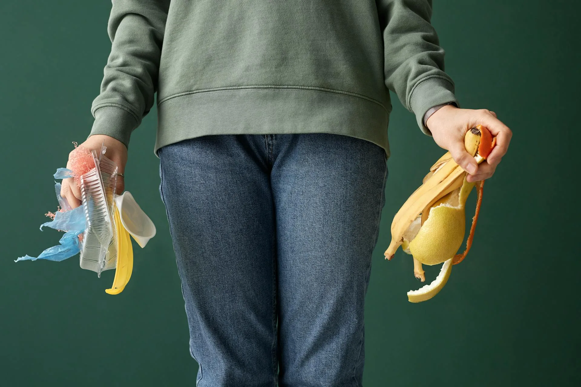 Person sorting fruit peelings and food scraps from plastic waste for composting