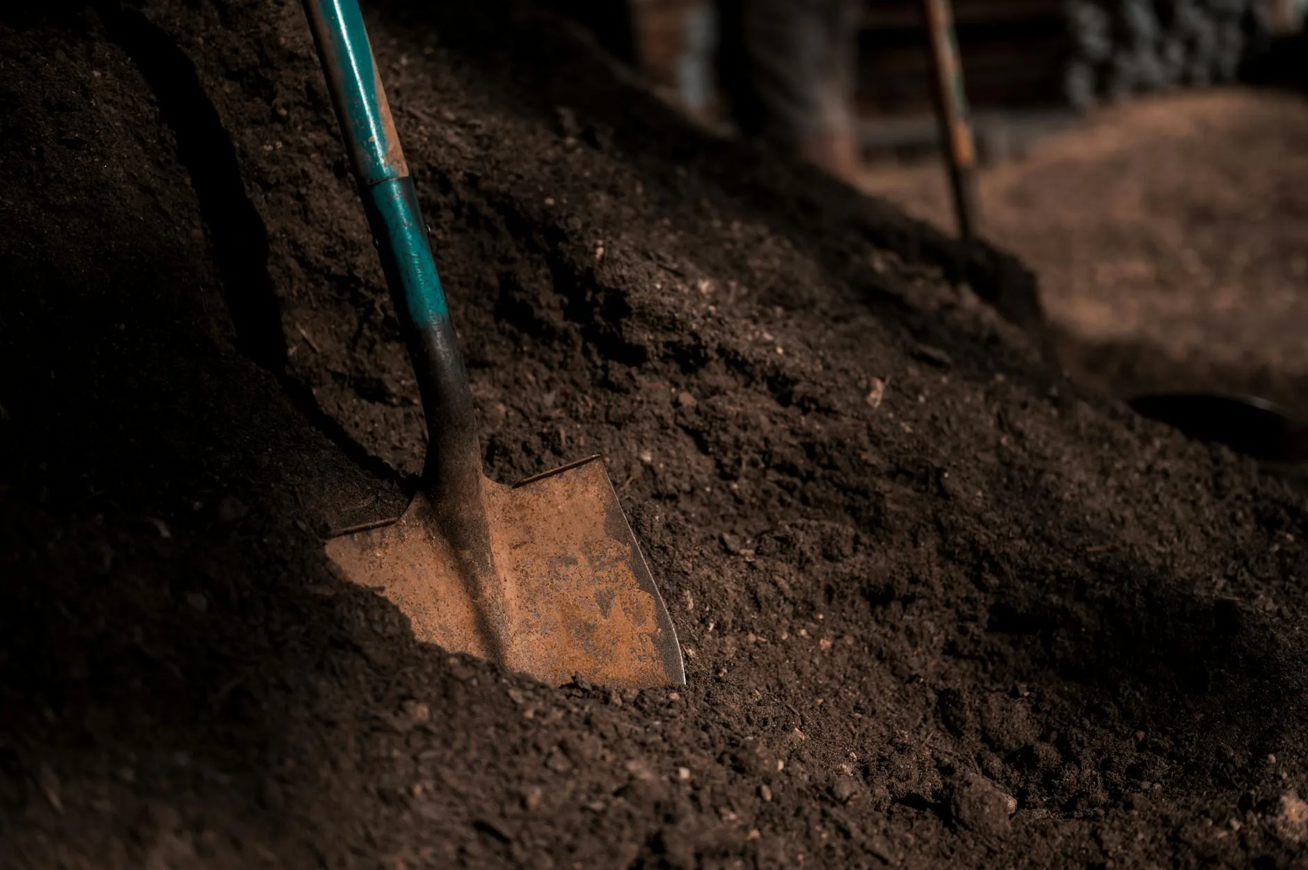 Garden fork turning a compost pile with steam rising from decomposing matter